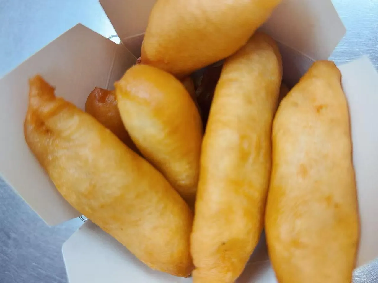 Golden fried dough sticks packed inside white paper takeout box at Silk Road Bistro, a Chinese Restaurant in Martiborough