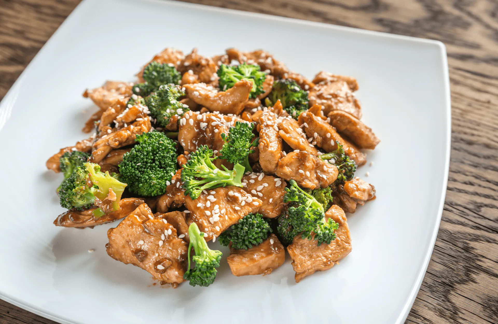 Teriyaki chicken stir-fry with broccoli and white sesame seeds on square plate at Silk Road Bistro, a Chinese Restaurant in Martiborough